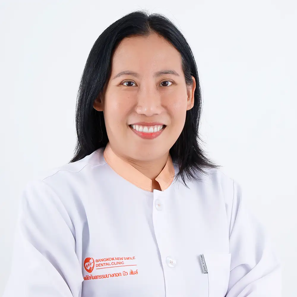 a portrait of a female dentist in a white gown smiling