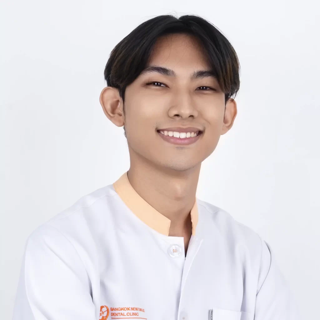 A photo of a male dentist wearing a white gown smiling at the camera
